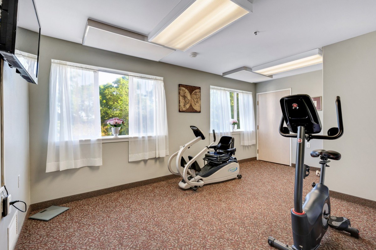 A bright and airy exercise room featuring cardio machines.
