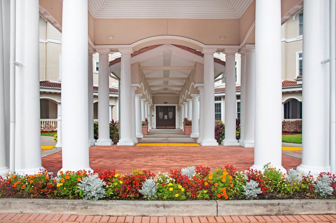 A symmetrical architectural entrance with white columns and vibrant flower beds.