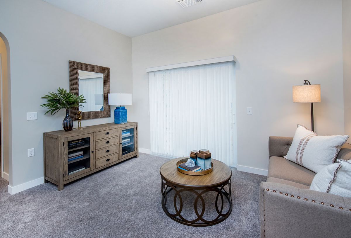 A modern living room featuring a comfortable sofa, stylish coffee table, and decorative elements including a large mirror and lamp.