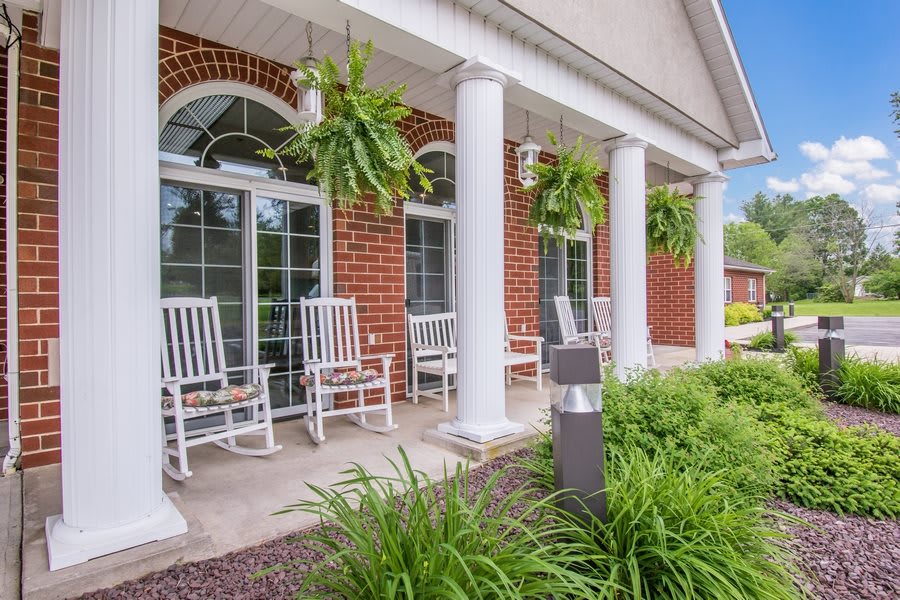 A charming porch with rocking chairs and hanging plants on a sunny day.