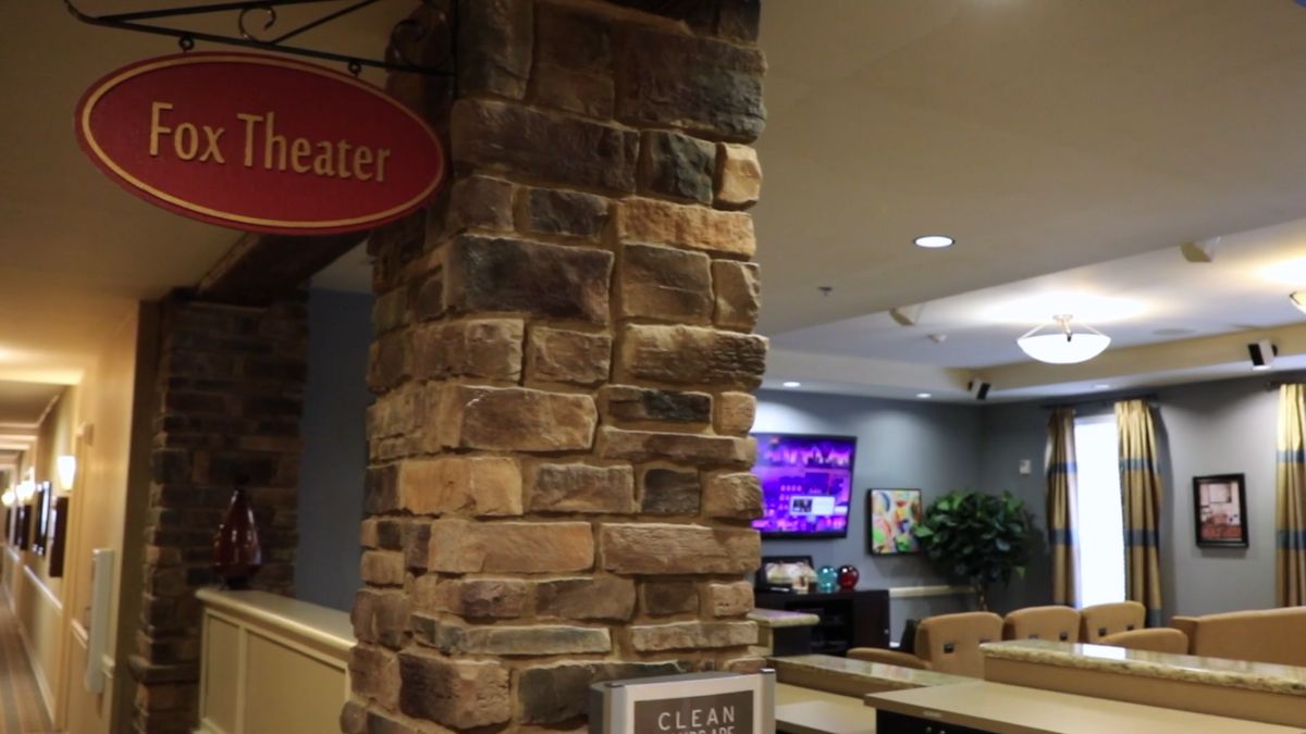 Interior view of a lobby featuring a brick pillar, signage, and a television.