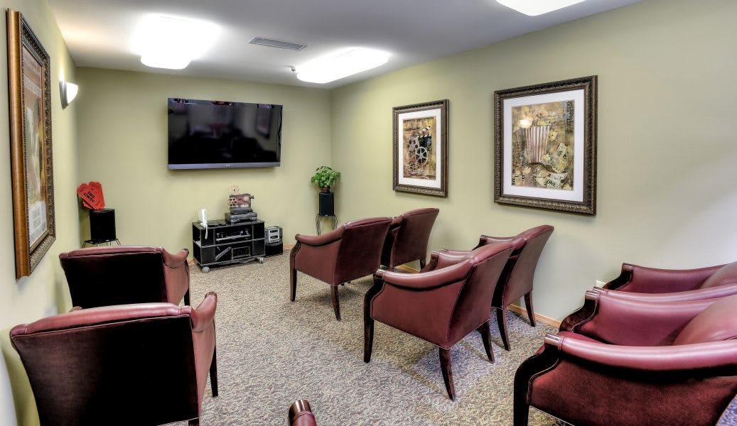 A comfortable waiting room with chairs, a television, and artwork on the walls.