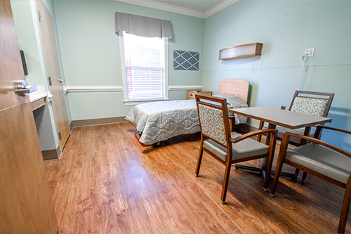 A well-lit and spacious hospital room equipped with essential furniture.