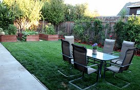 A backyard garden with a patio set and lush greenery.