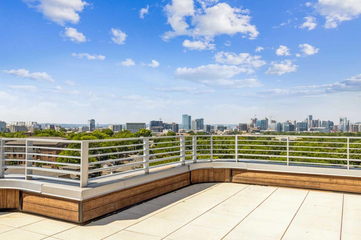 A spacious rooftop deck overlooking a city skyline under a clear blue sky.