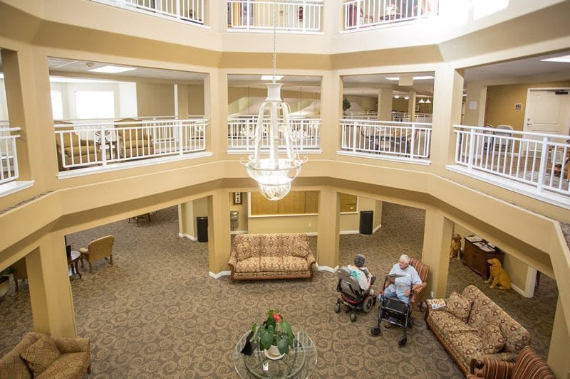 A spacious lobby with a chandelier, seating areas, and two people conversing.