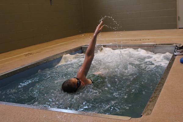 Person swimming in an indoor pool exercising with a backstroke.