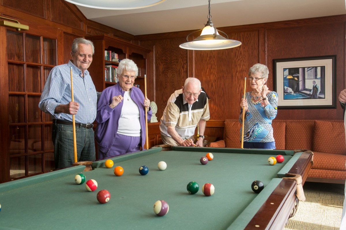 A group of seniors playing billiards together in a cozy indoor setting.