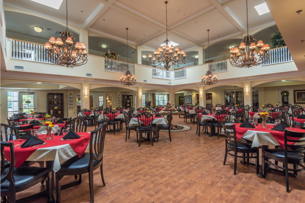 A spacious and elegantly decorated dining room with chandeliers and set tables.