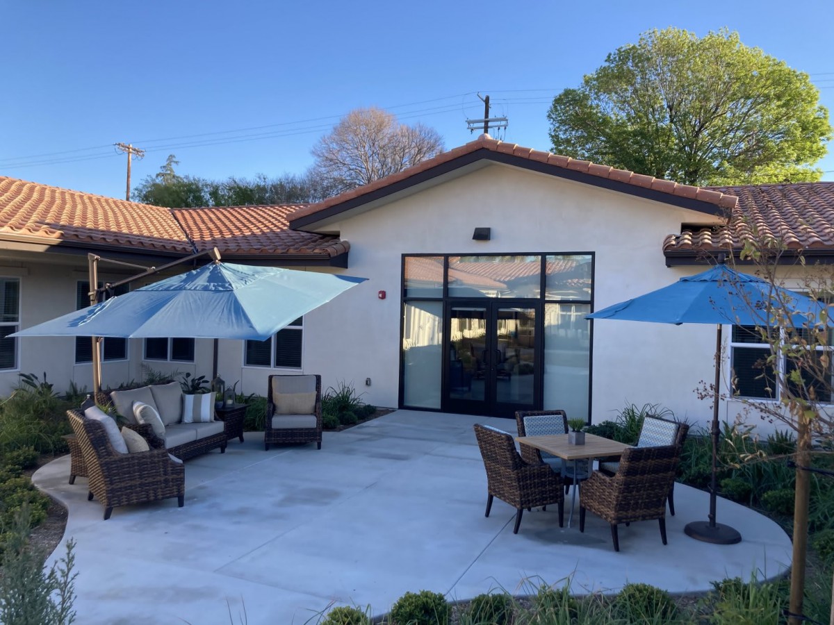 A modern outdoor patio with furniture and umbrellas on a sunny day.