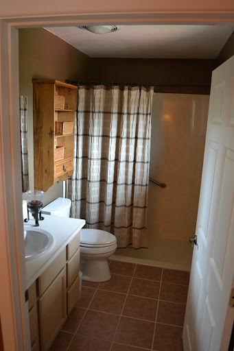 A tidy bathroom featuring a shower area, toilet, and sink with wooden storage.