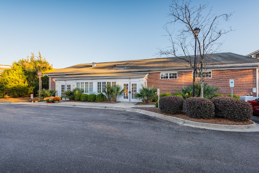 A picturesque view of a modern building surrounded by landscaped greenery and a clear blue sky.