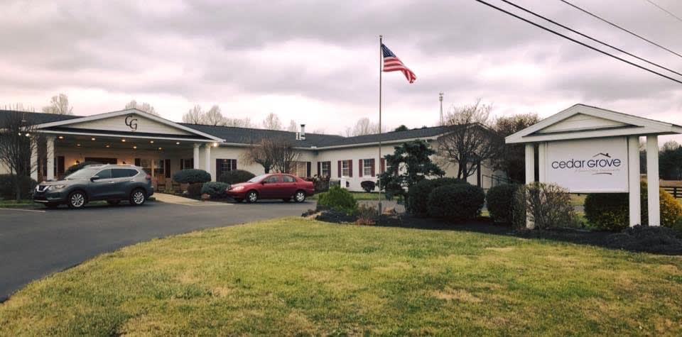 A small building with an American flag flying outside, a red car parked nearby, and a cloudy sky overhead.