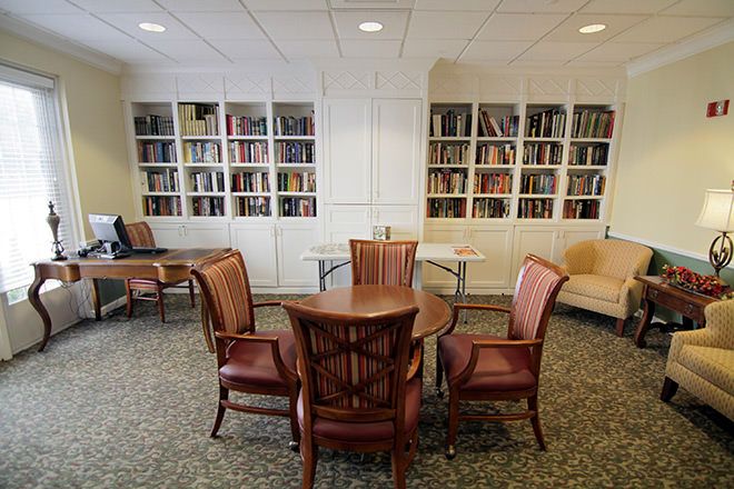 A cozy library reading area with bookshelves, a round table, and four chairs.