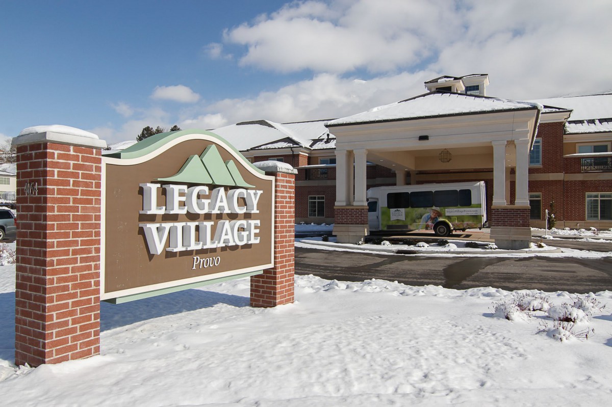 A winter scene featuring the Legacy Village building and sign, surrounded by snow.