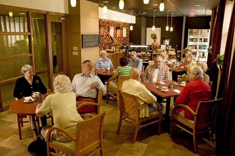 A group of seniors socializing and dining in a restaurant setting.
