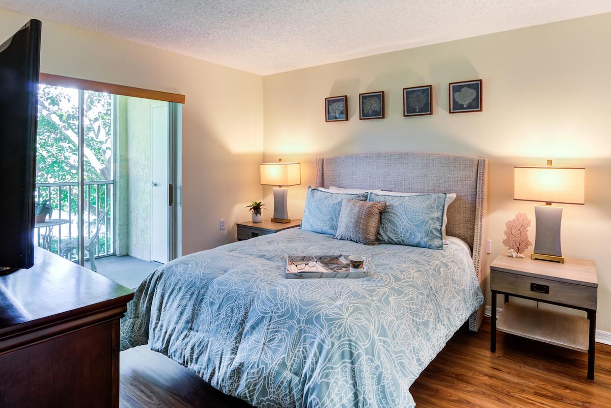 A cozy and elegantly decorated bedroom featuring a comfortable bed with blue bedding, bedside tables with lamps, and framed art on the wall.