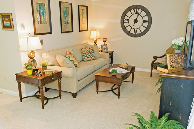 A cozy living room with a comfortable sofa, coffee tables, and stylish decor including a large wall clock and artwork.