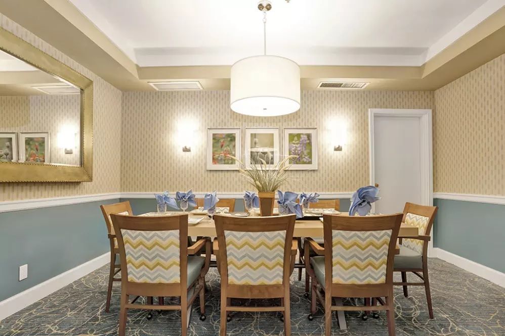 A well-decorated dining room featuring a wooden table with matching chairs, adorned with elegant decor and illuminated by a ceiling light.