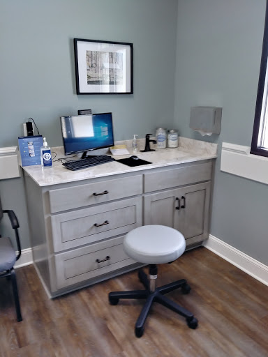 A modern medical office workspace featuring a desk with a computer and ergonomic chair.