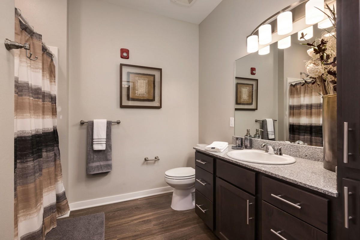 A modern bathroom with a double sink vanity, wall art, and warm lighting.