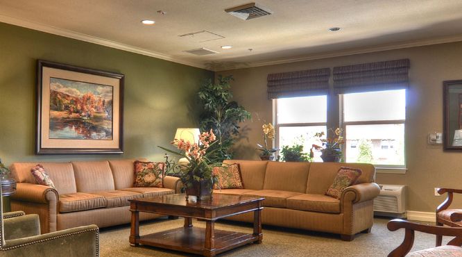 A cozy and elegant living room with a large sofa, wooden coffee table, decorative plants, and wall art.