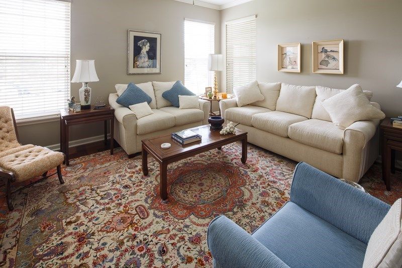 A cozy living room with two beige sofas, a wooden coffee table, and a patterned carpet.