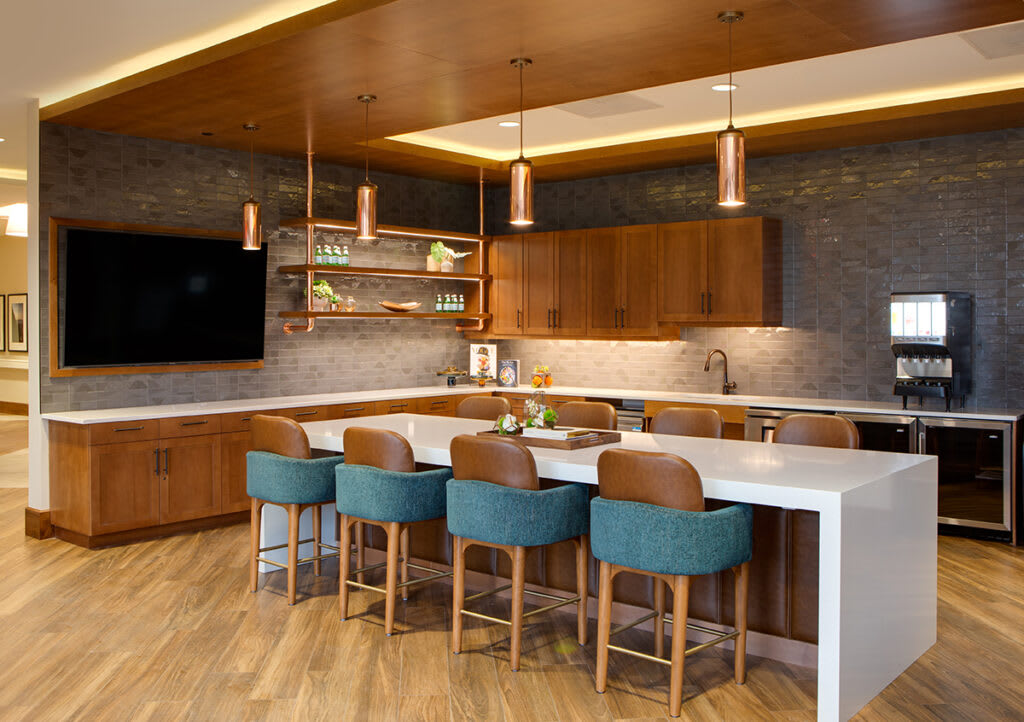 A modern kitchen with wood cabinets, an island counter, and stylish bar stools.
