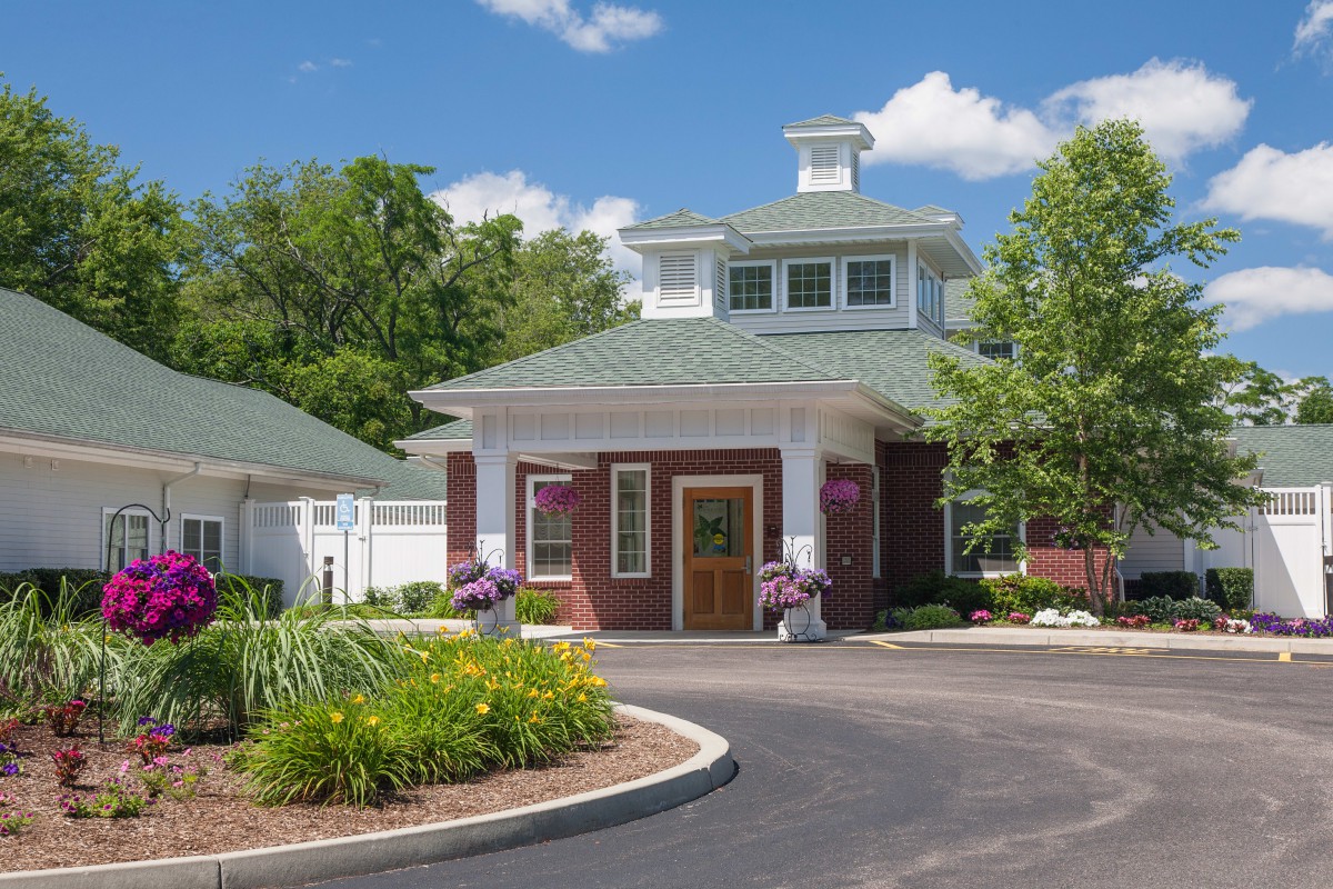 A charming small building with a landscaped garden and driveway in front.