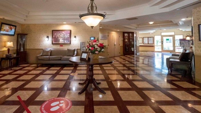 A spacious lobby with elegant decor, featuring a central table with flowers, comfortable seating, and decorative lighting.