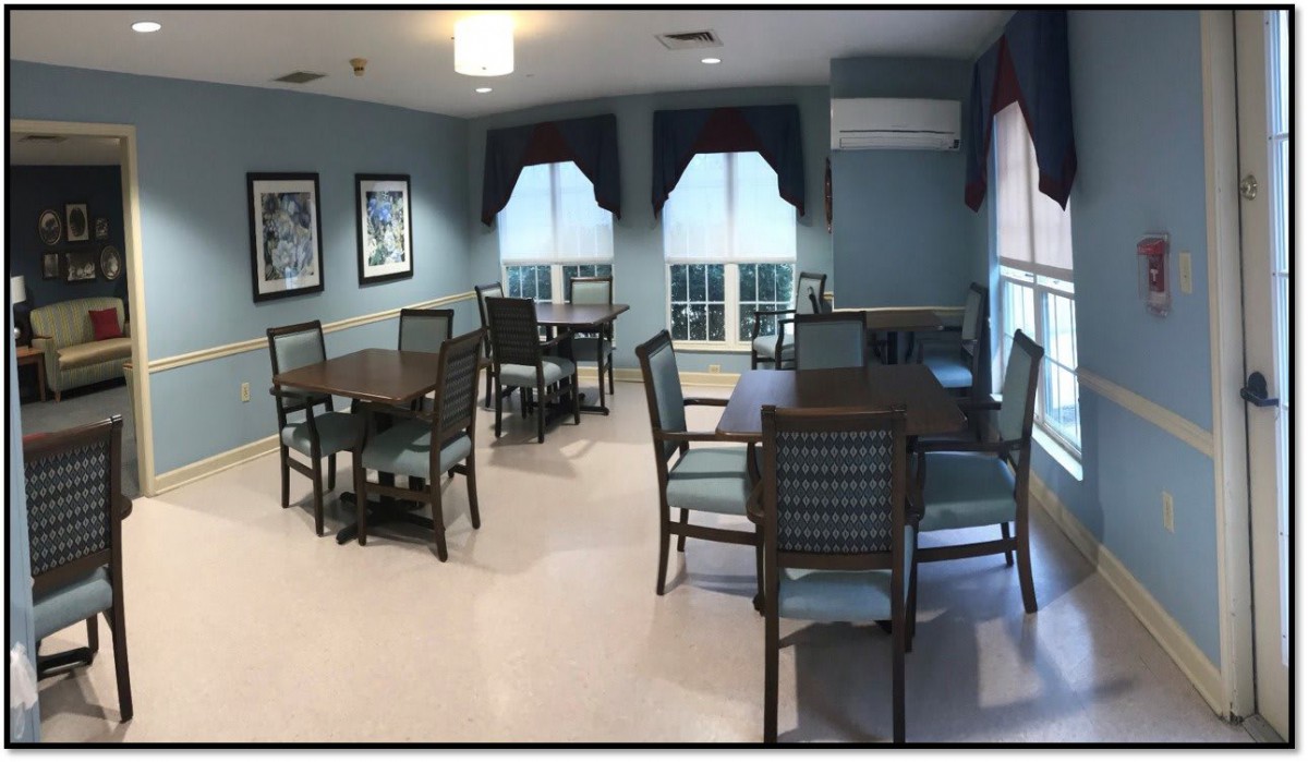 A cozy dining room with multiple tables and chairs arranged near large windows, featuring soft lighting and elegant decor.