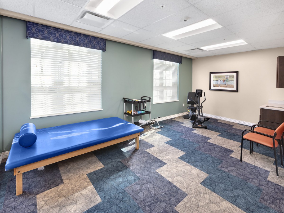 A modern physical therapy room featuring a treatment bed and exercise equipment.