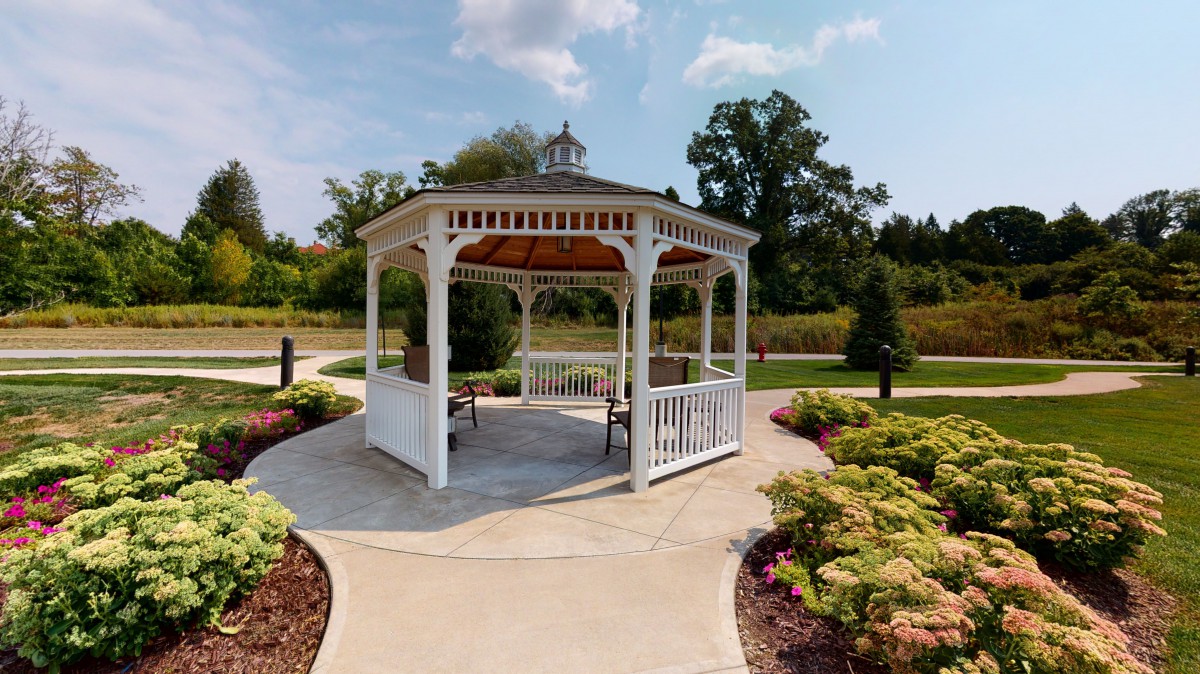 A picturesque white gazebo surrounded by a landscaped garden and paved pathways.