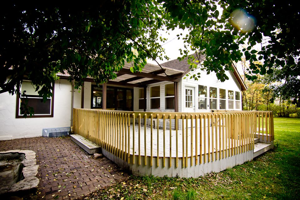 A charming house with a wooden deck surrounded by lush trees.
