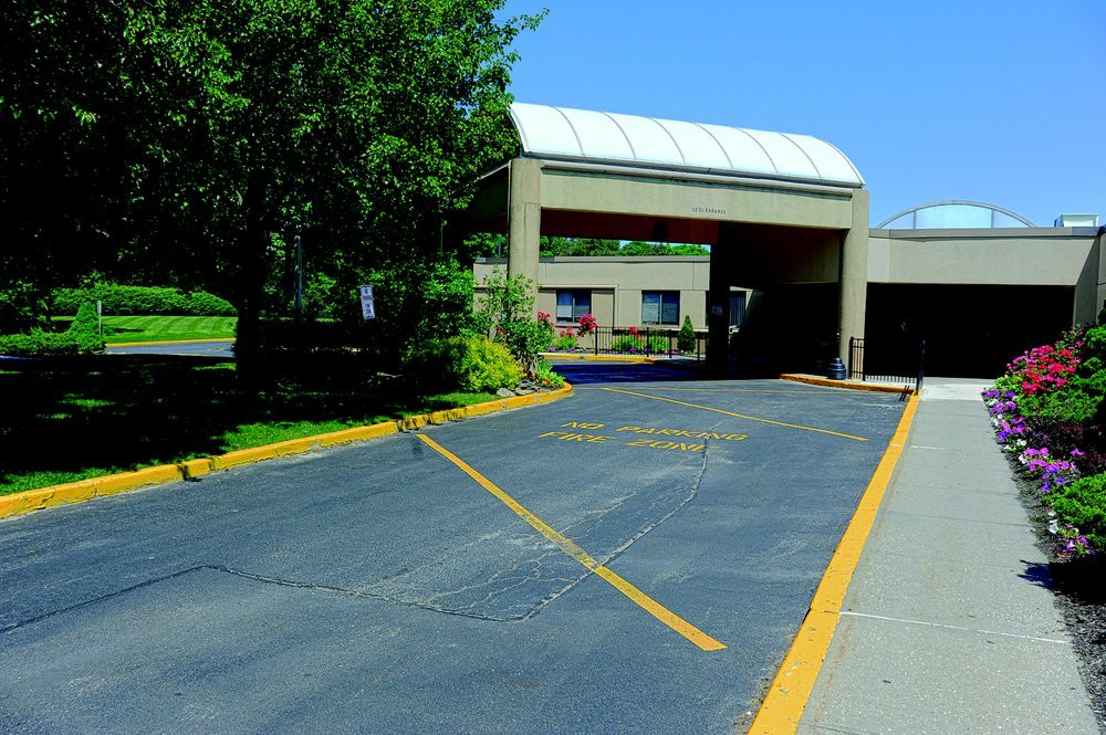 A drive-thru area outside a building with surrounding trees.