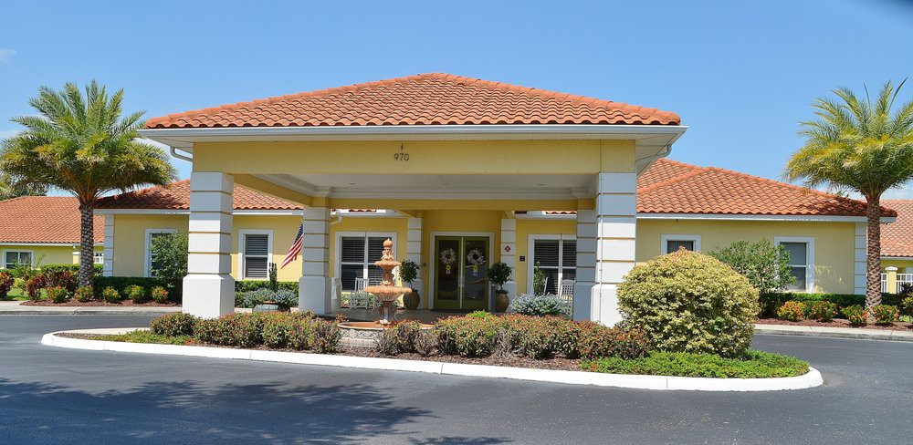 A well-maintained building entrance with a covered driveway and landscaped surroundings.