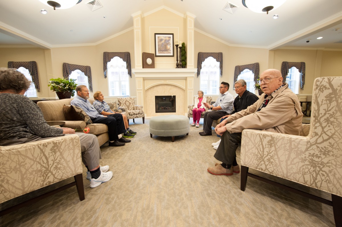 A group of elderly people sitting in a comfortable living room, engaged in a casual meeting.
