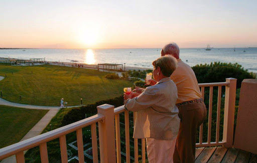 A serene sunset view shared by an elderly couple, enjoying each other's company at the beach.