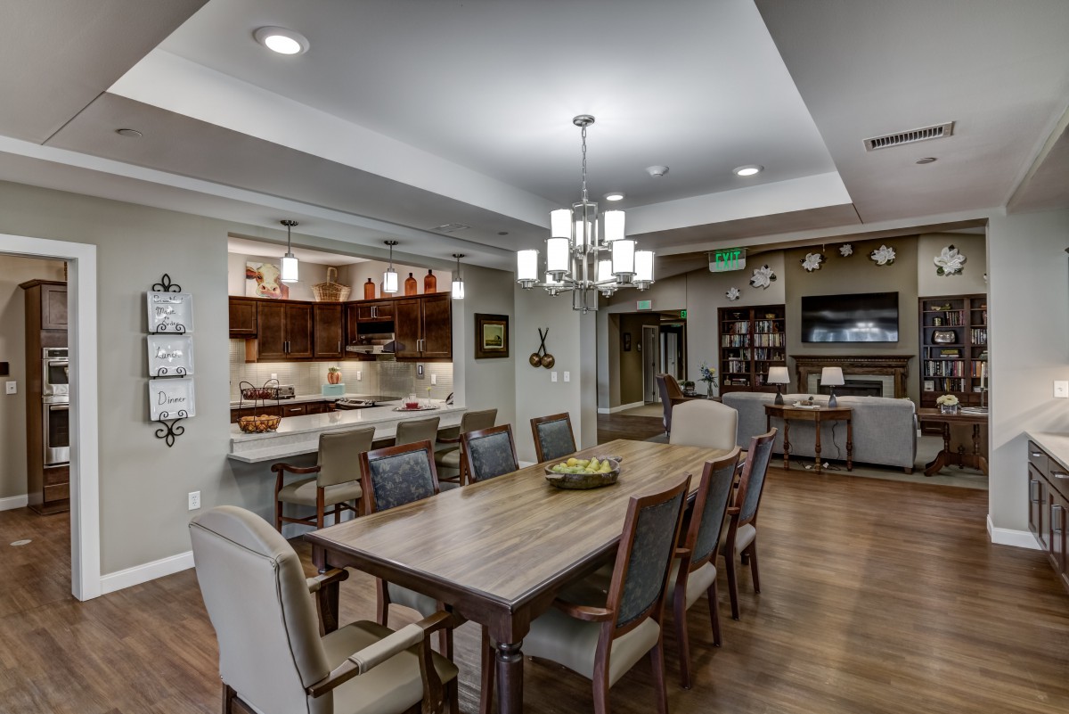 A modern open concept dining area connected to a kitchen with elegant lighting and furnishings.
