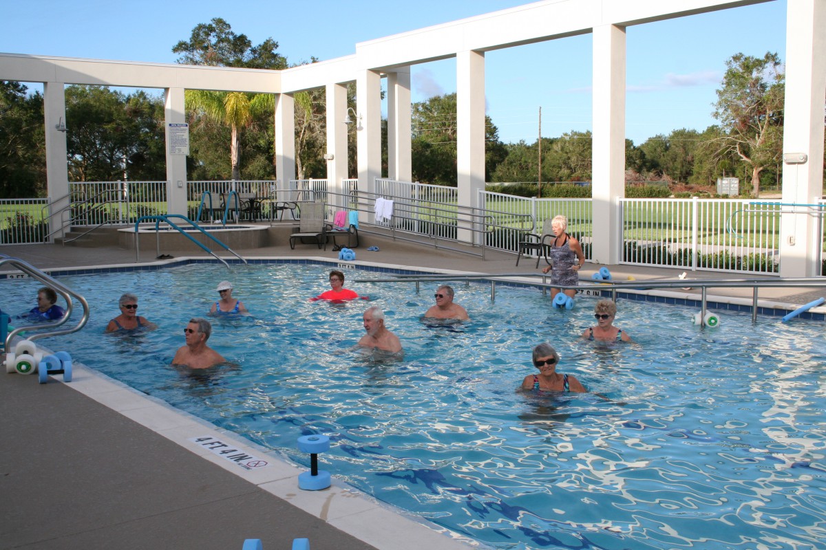 Group of people participating in a water aerobics class in an outdoor swimming pool.