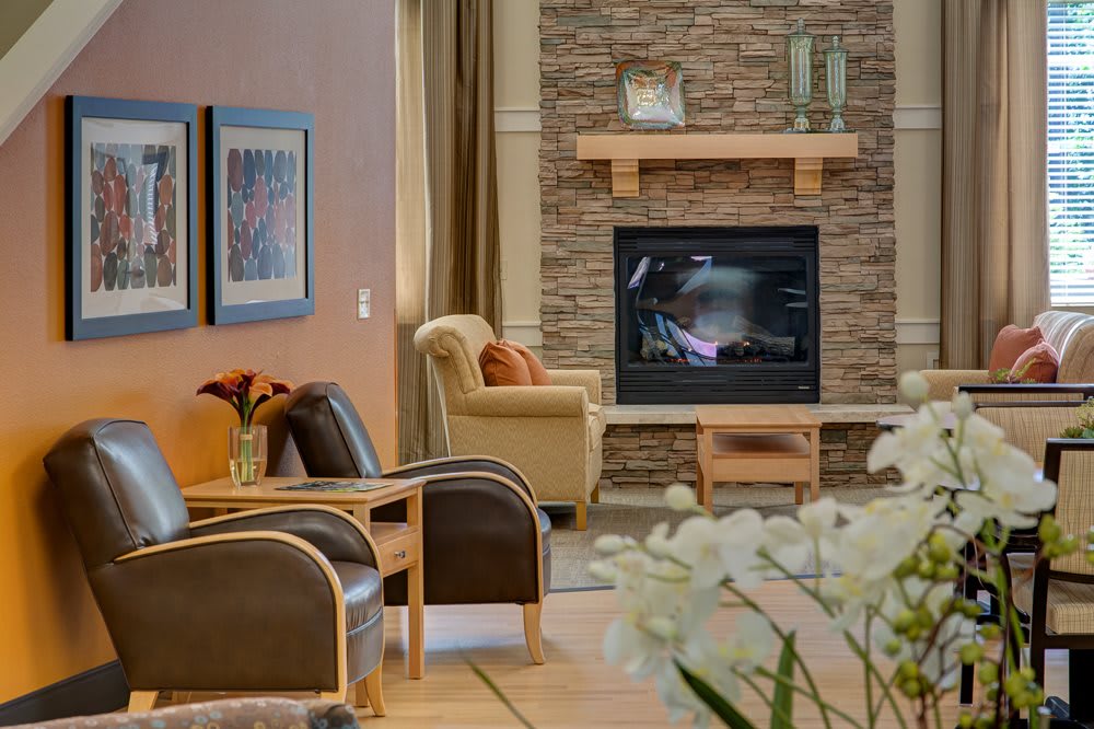 A cozy living room with a stone fireplace, comfortable seating, and decorative artwork on the walls.
