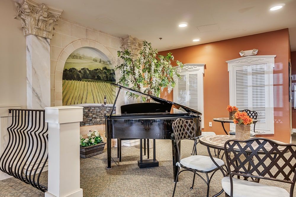 A cozy living room featuring a grand piano, decorative mural, and indoor seating area.