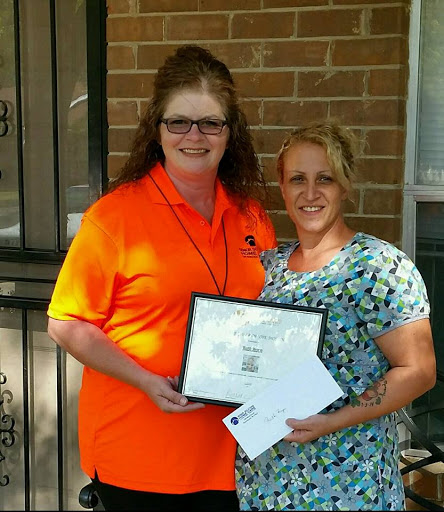 Two women proudly posing with a certificate and documents, celebrating an achievement.
