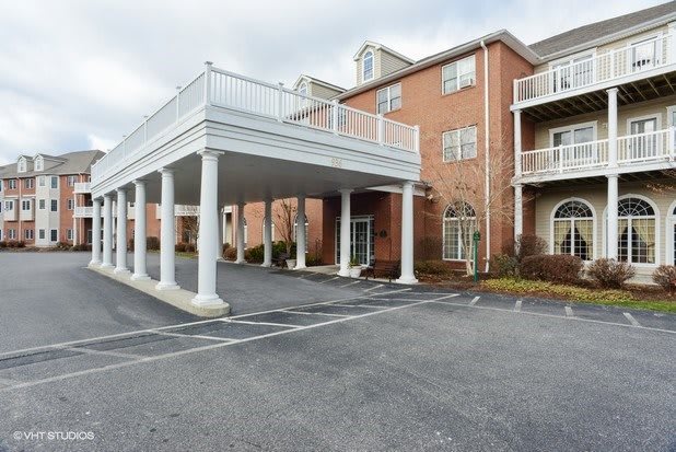 A brick hotel building with a covered driveway and parking lot.
