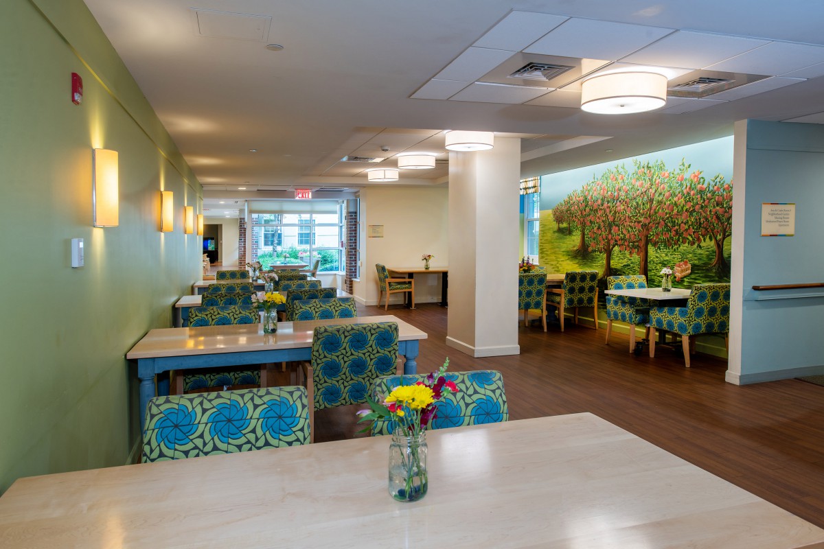 A brightly decorated restaurant dining area with floral arrangements on tables and colorful seating.
