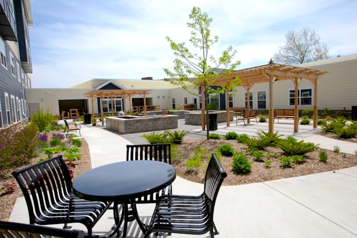 An outdoor patio area with tables and chairs surrounded by landscaped gardens.