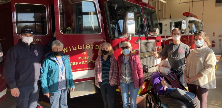 A group of people standing in front of a fire truck at the Williston Fire Department, wearing masks.