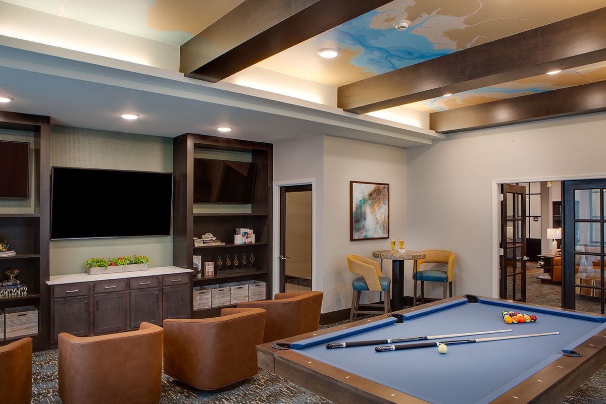 A modern game room featuring a pool table, comfortable seating, and a large television.