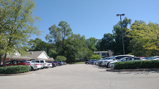 A spacious parking lot surrounded by greenery under a clear blue sky.