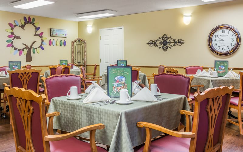 An elegantly set dining room table with folded napkins and comfortable seating.